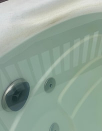 Dirty hot tub side and green water.