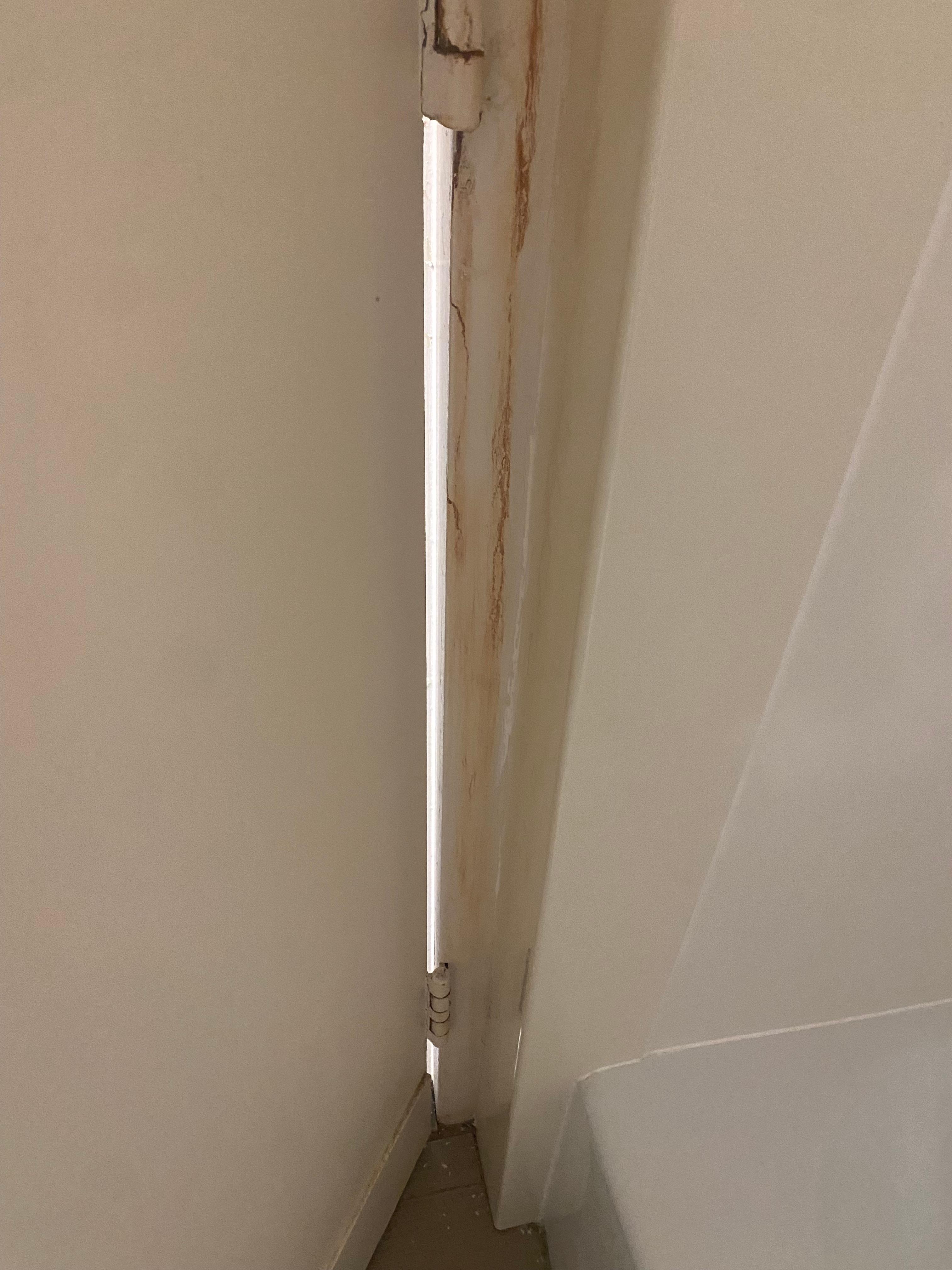 Brown rust liquid dripping down wall of bathroom 