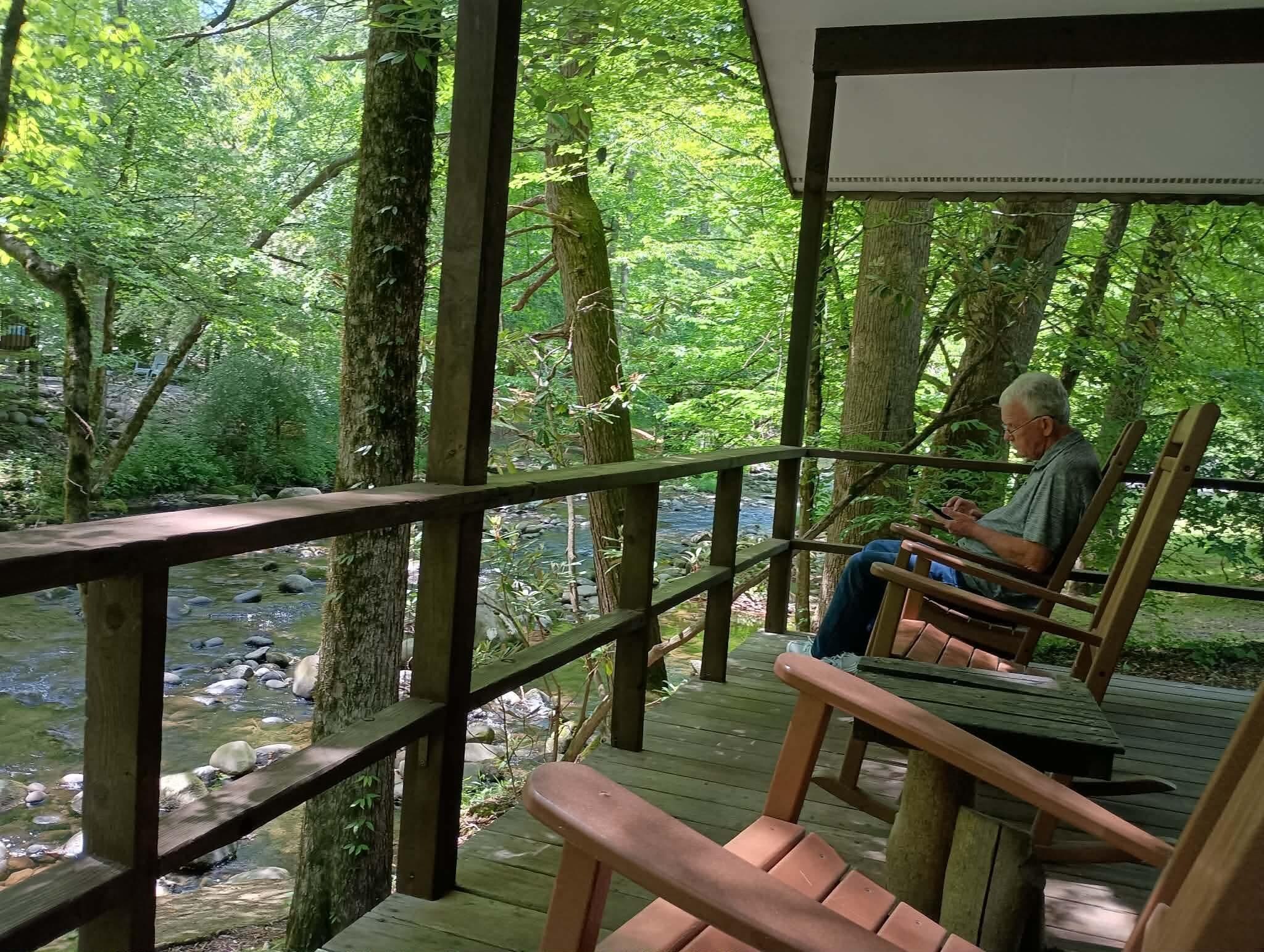 The porch on the creek with 6 available rocking chairs. WONDERFUL. Greenbrier Camping is on the other side of the creek but no problem with that.