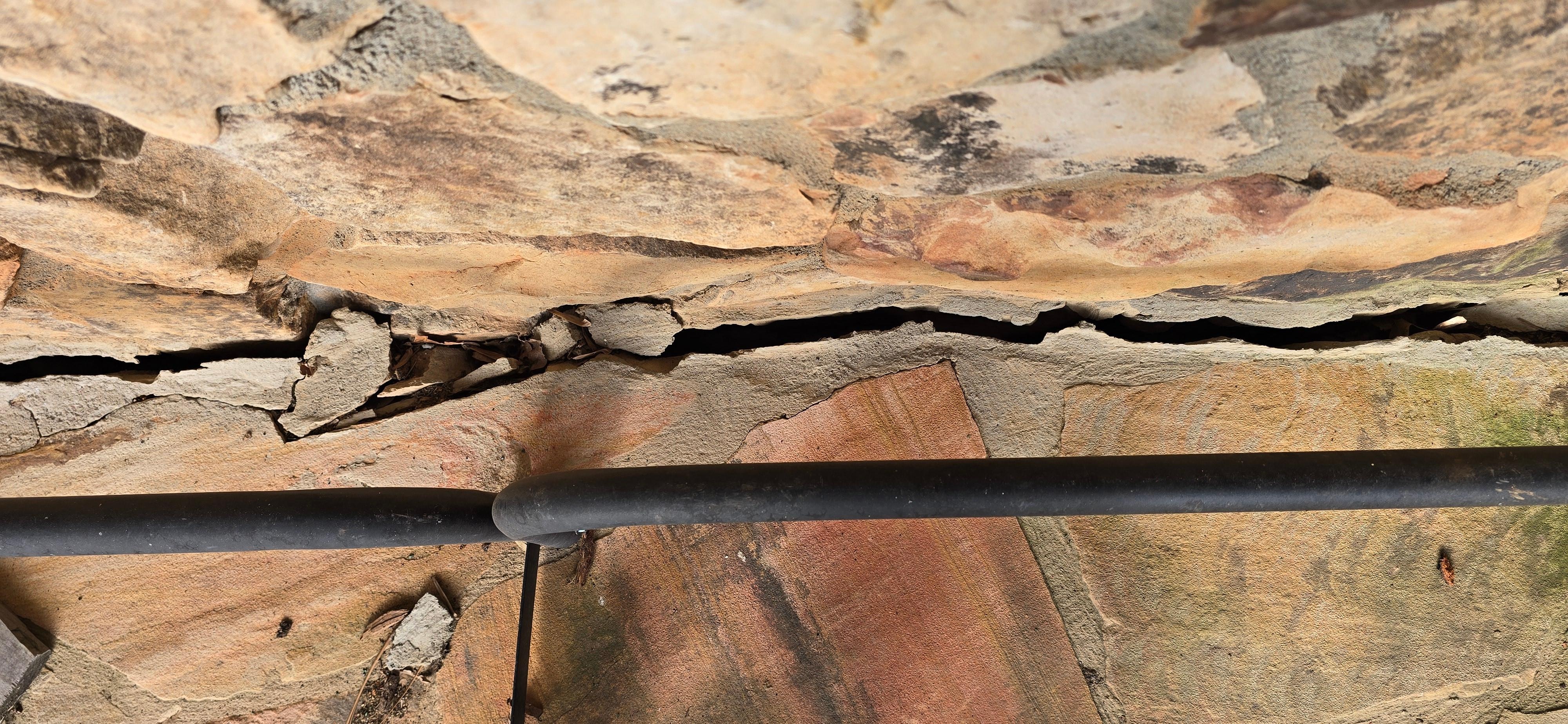 Picture shows the 1" crack where the stone patio is pulling away from the house and going down the mountain. This patio will collapse eventually.