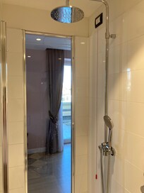 Brusekabine med akvarielignende udsyn til stue og byens tage.