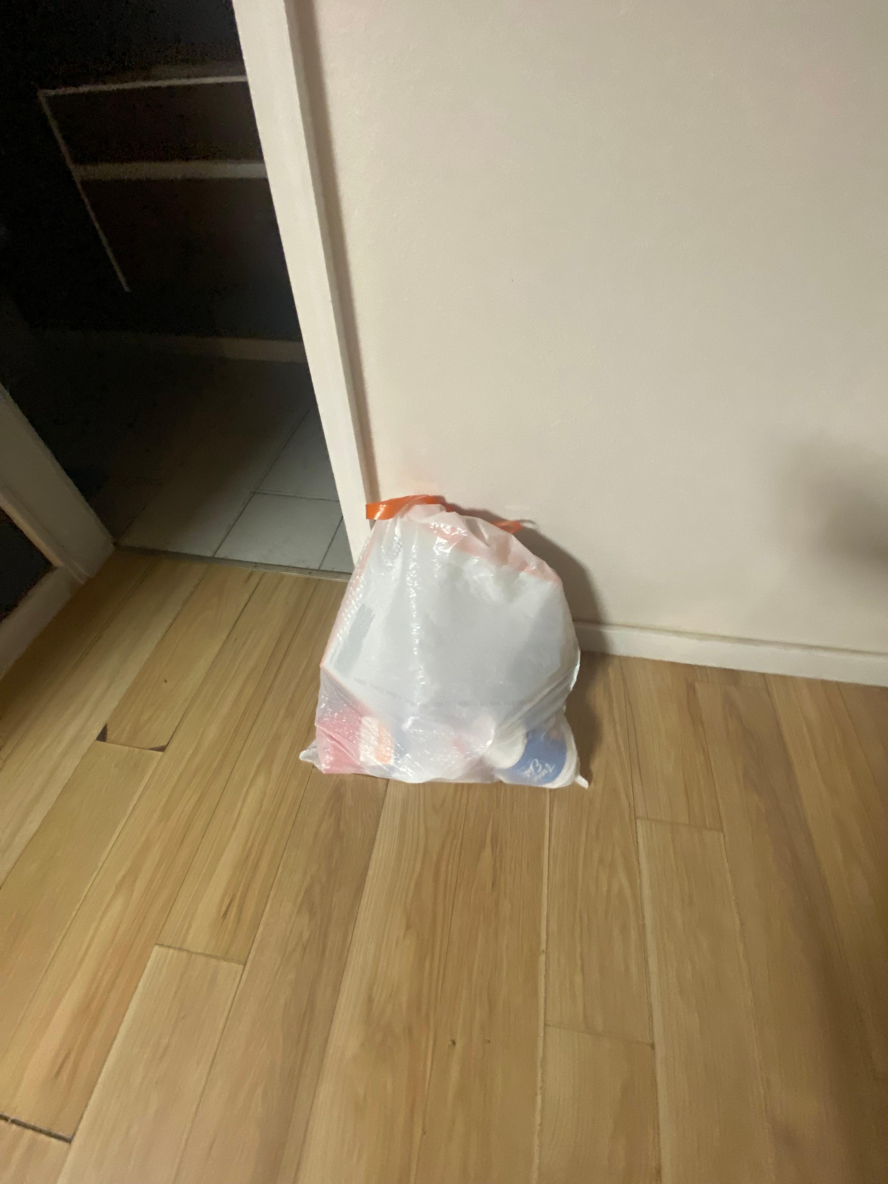 Full bag of trash left in living room area.