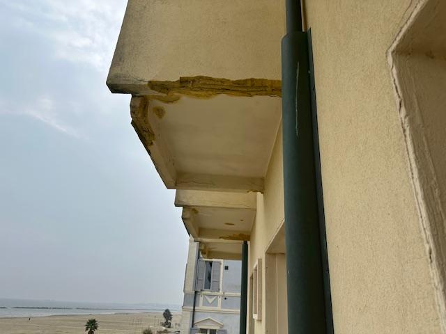 BROKEN OFF COCRETE PIECES OF STRUCTURE UNDERNEATH OF BALCONIES  ABOVE !