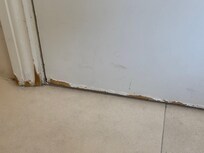 The bathroom door has water damage on the bottom to half way up the door