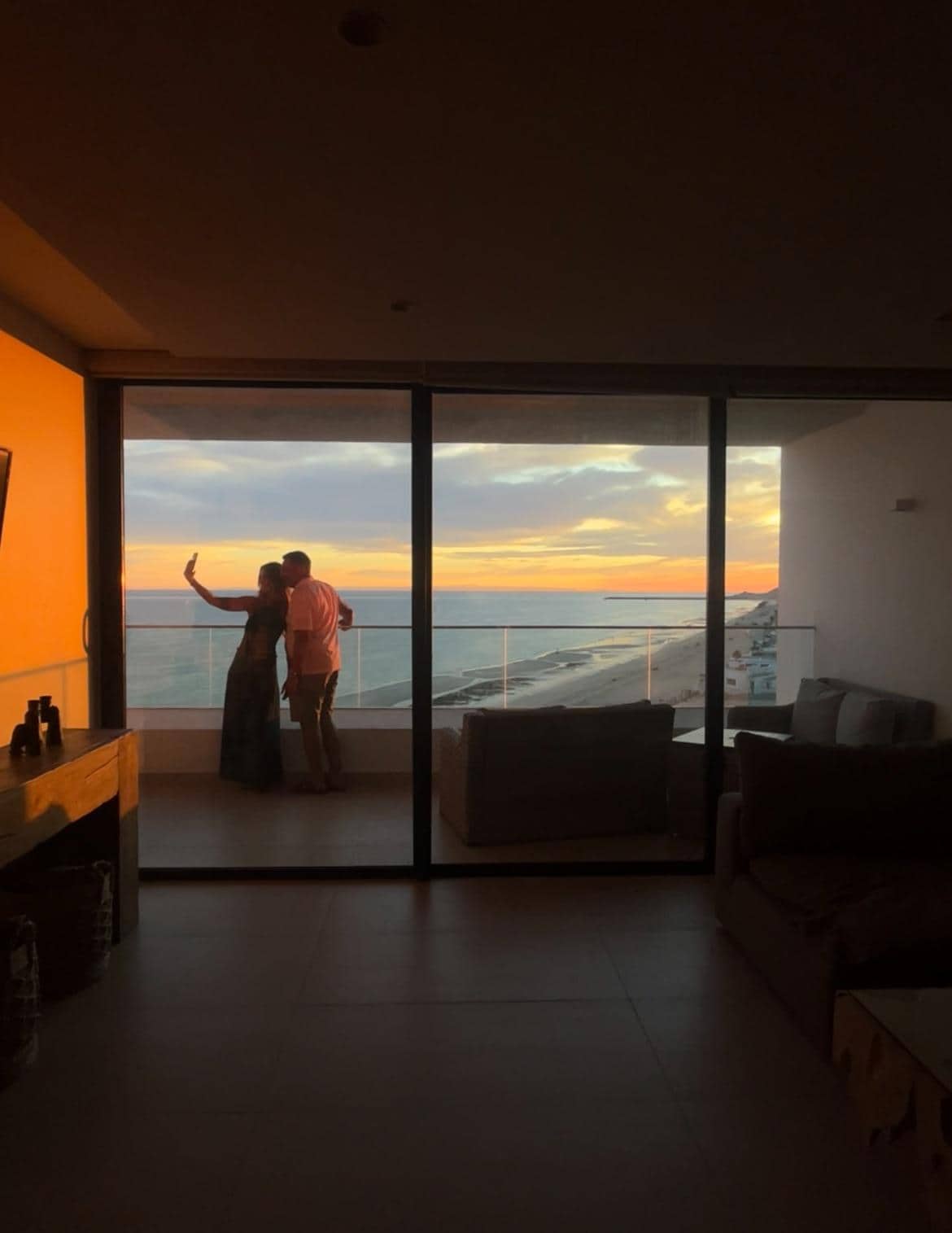 My daughter taking a picture of my husband and I taking a sunset selfie on the balcony.