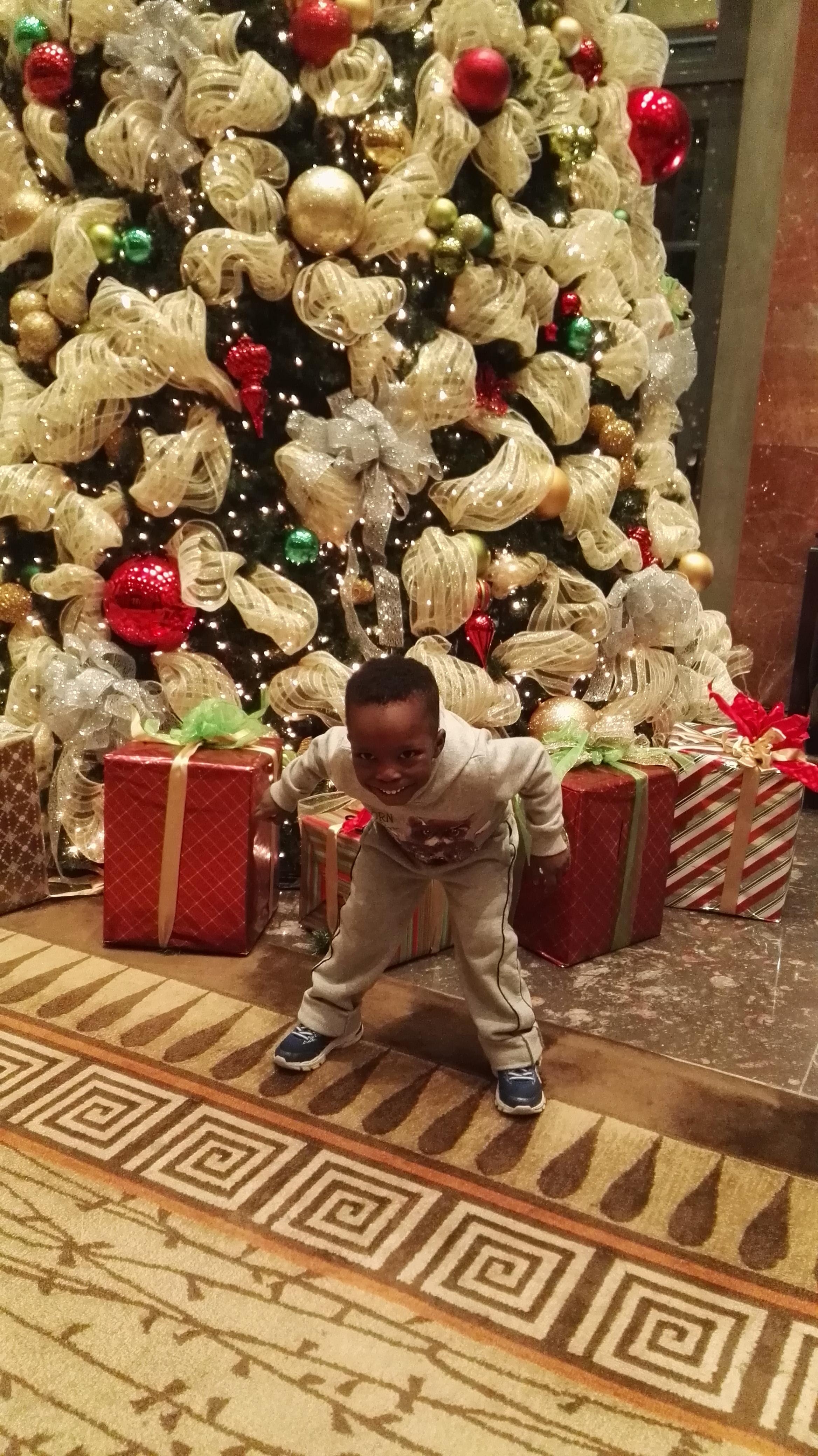 My son posing by the beautiful Christmas tree