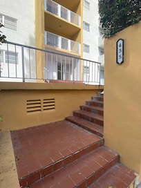 Entry to the building. Dog poop next to stairs on sidewalk.