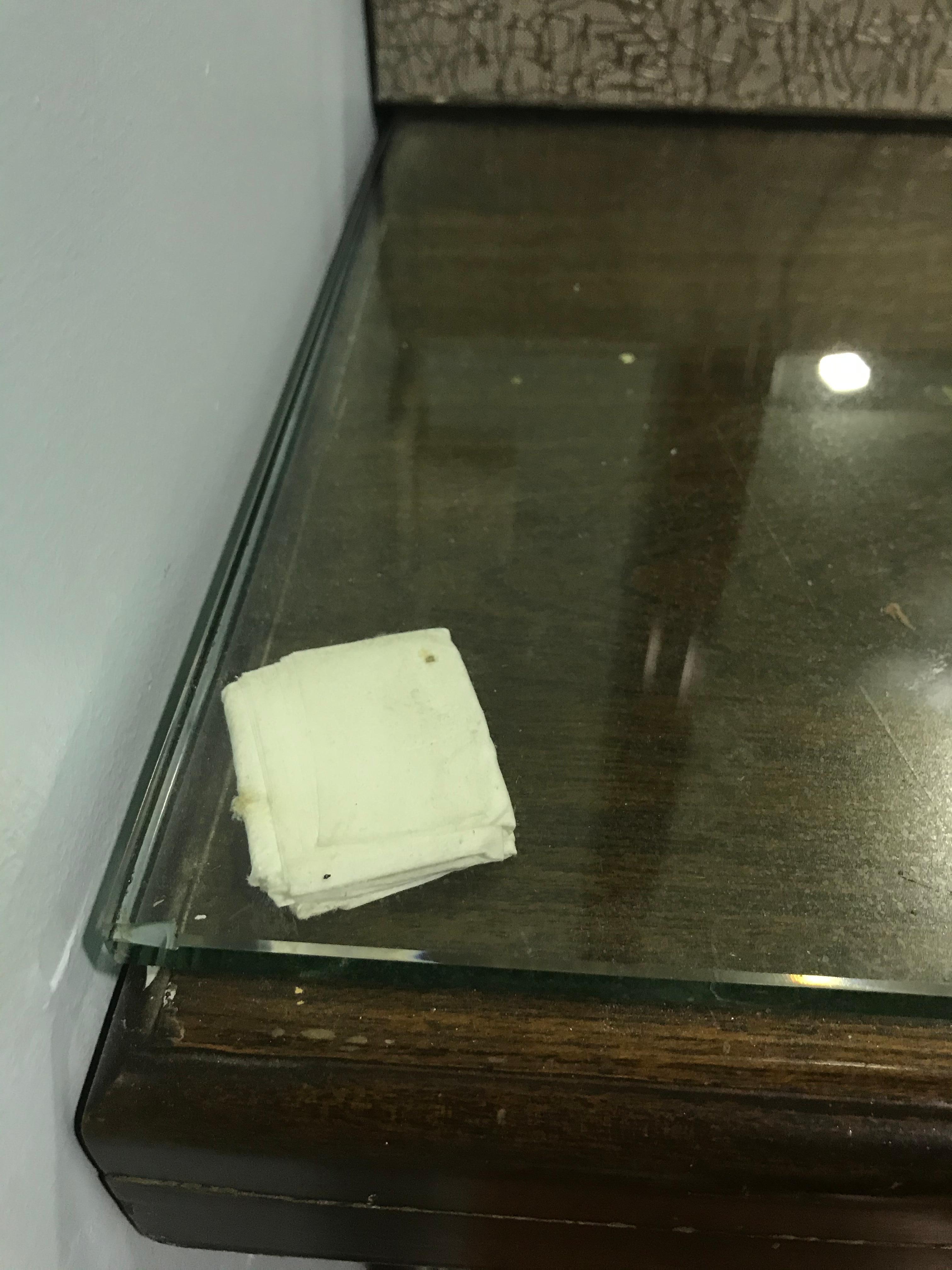 Used tissue holding up the glass top of the bureau