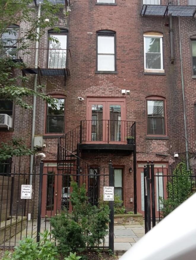 Back of apartment with a small patio and parking spots.