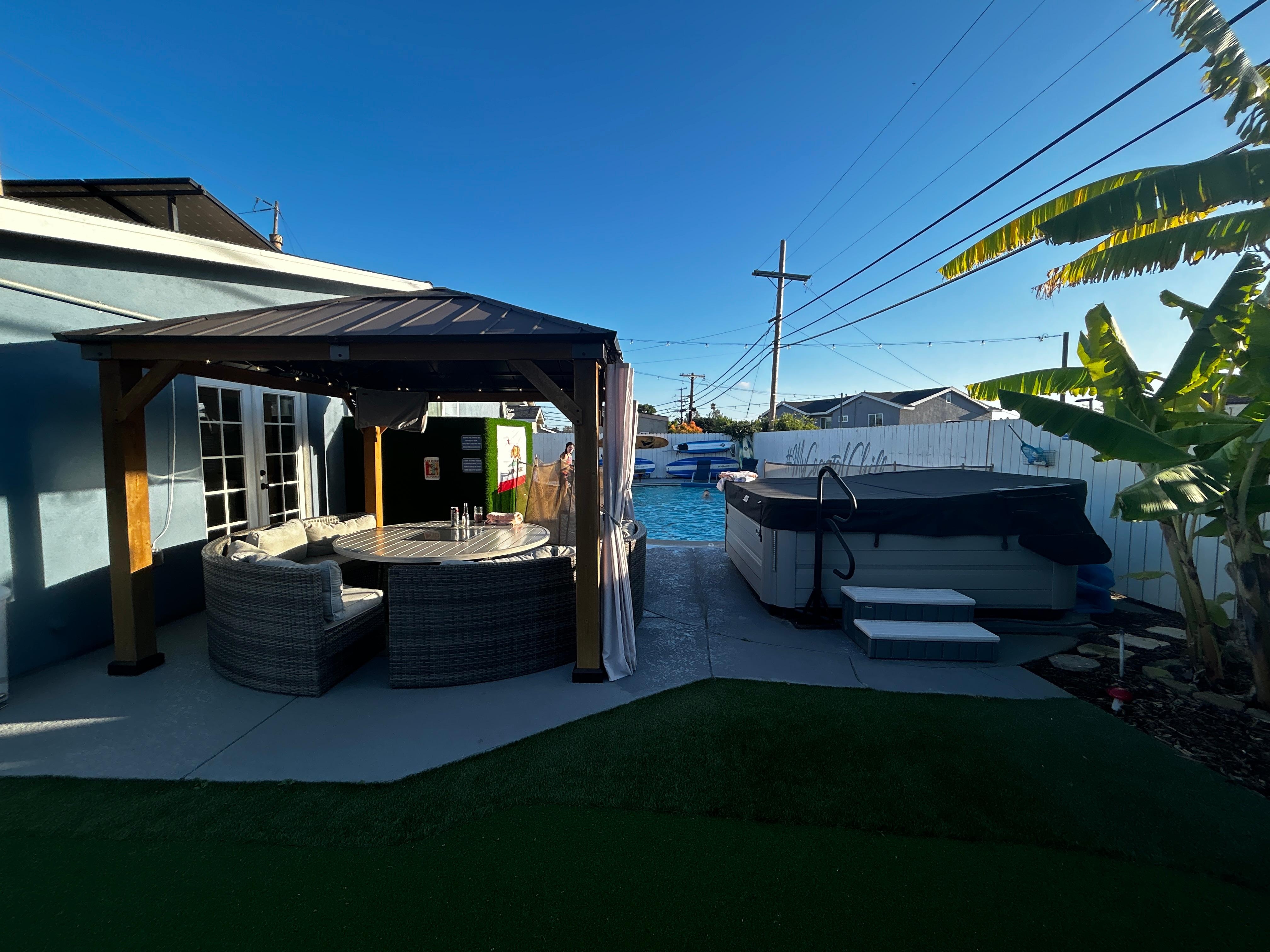View of gazebo with seating. fire table and hot tub