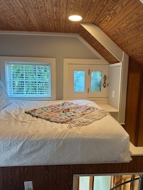 Treehouse bed, bird watching out window.