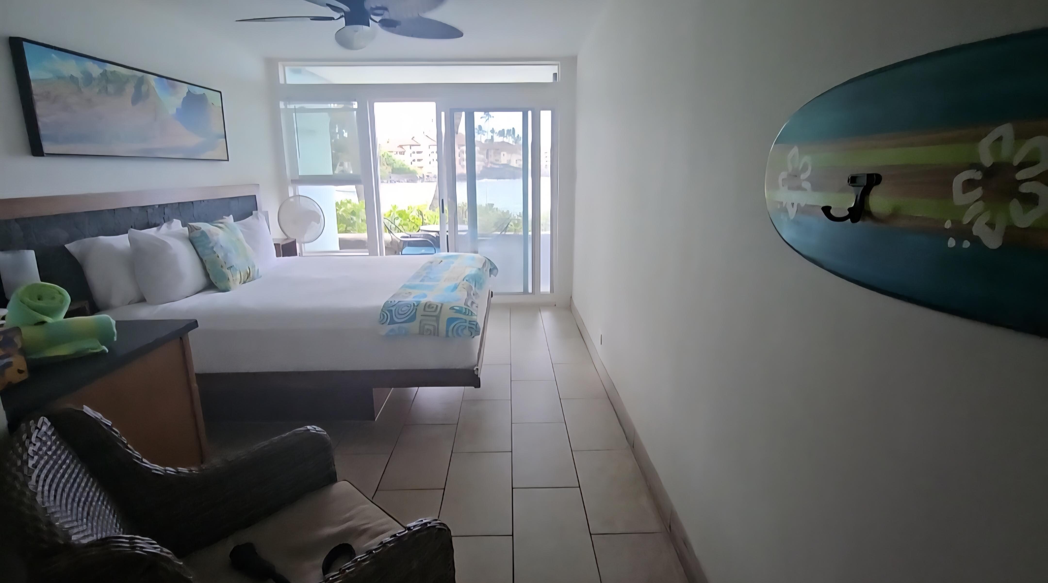Room has fans and outdoor porch with table chairs to sit and enjoy the beautiful waves and view