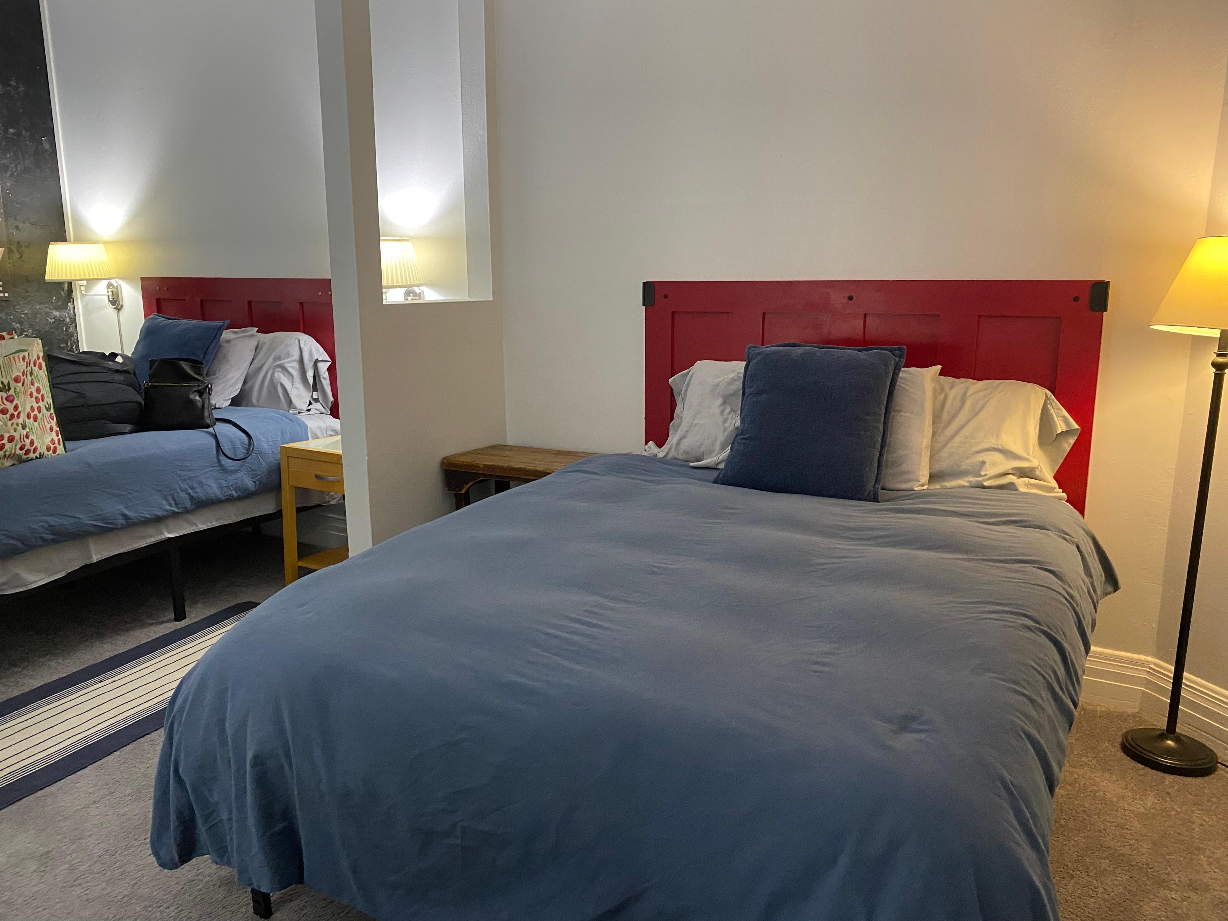 Two queen beds in one large room separated by a partition. 