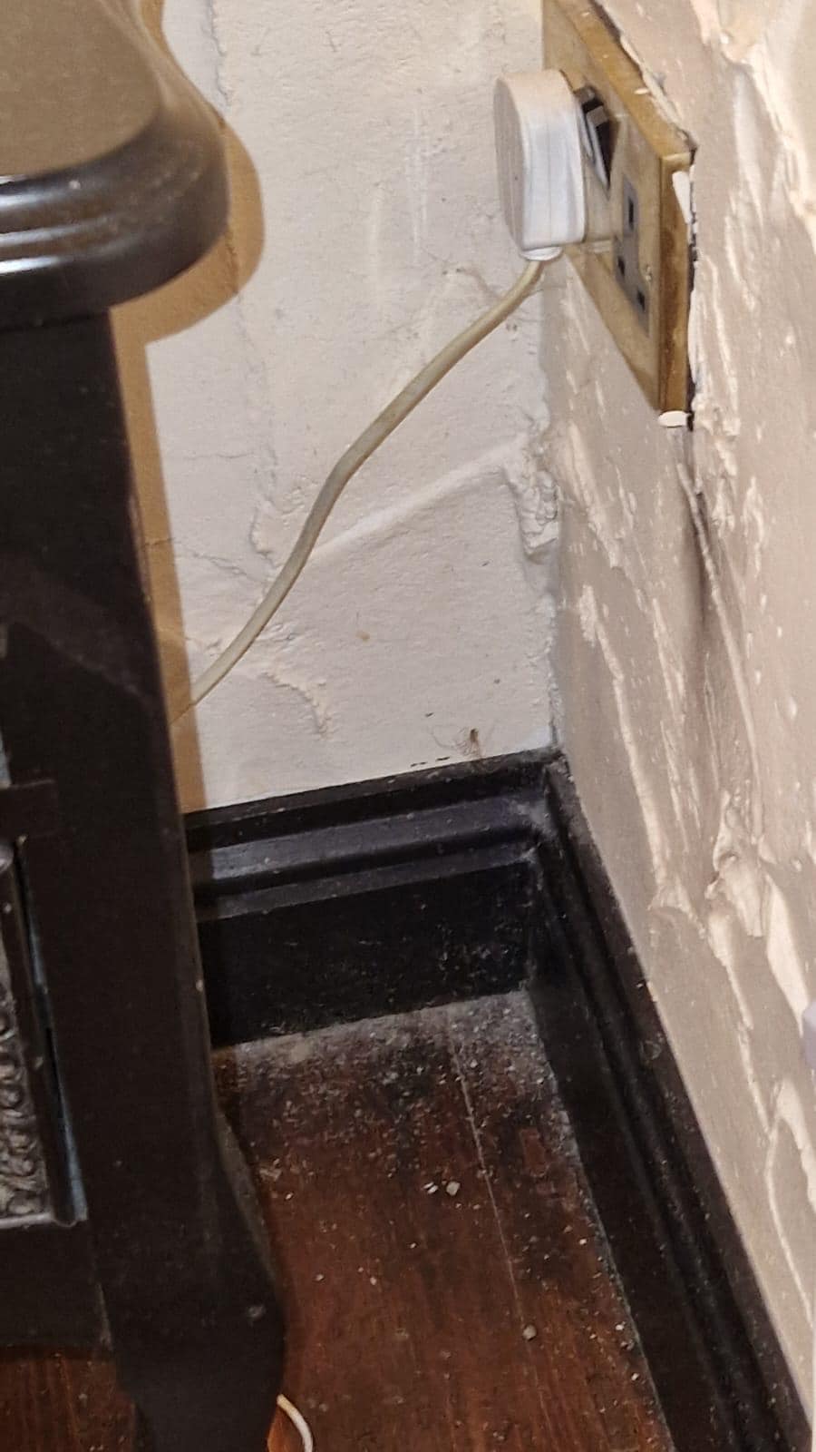 Aranha e muito pó ao lado da mesa de cabeceira. 