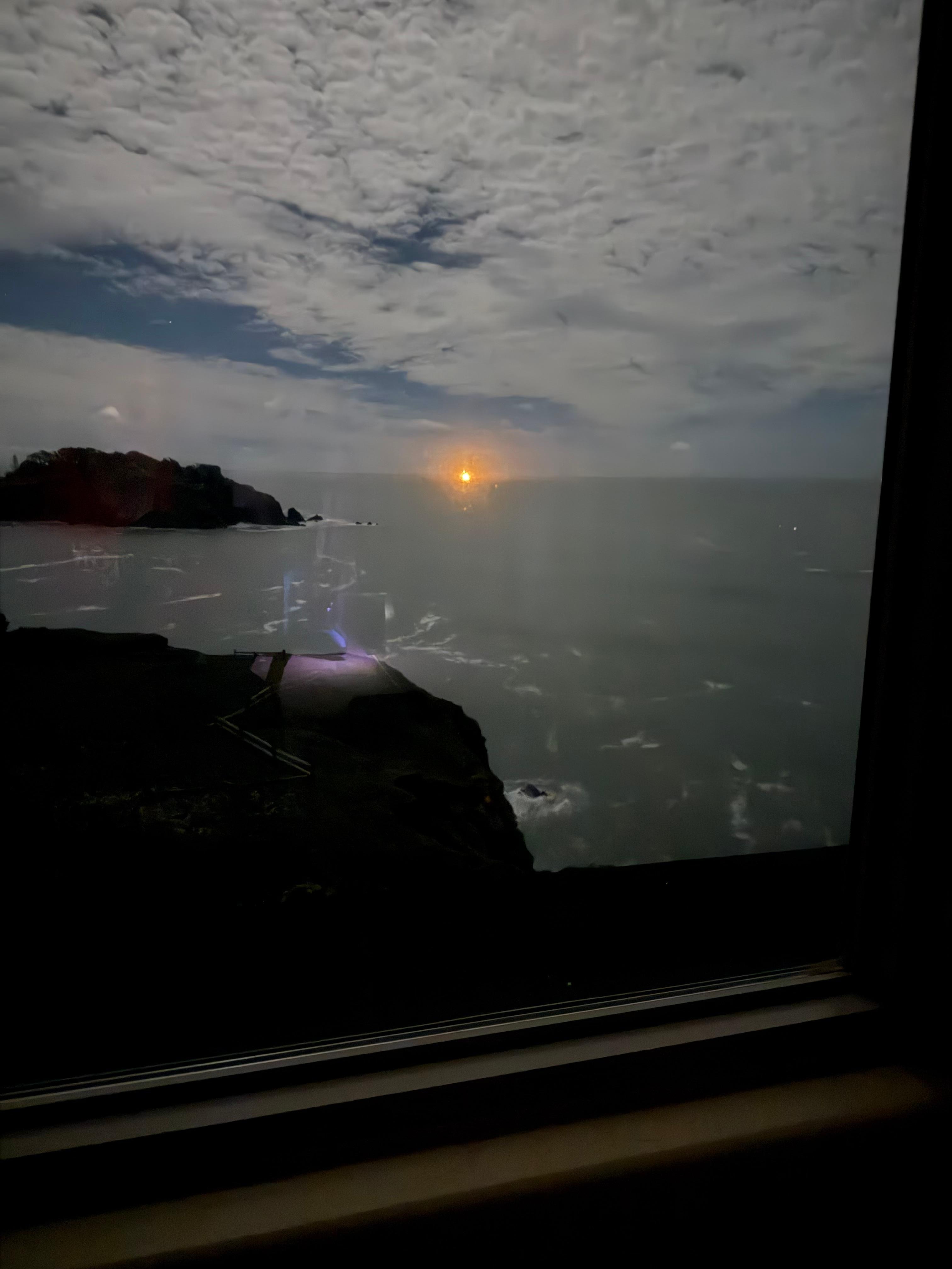 Cargo ship beacon on the horizon with a moonlit night sky.