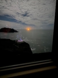 Cargo ship beacon on the horizon with a moonlit night sky.