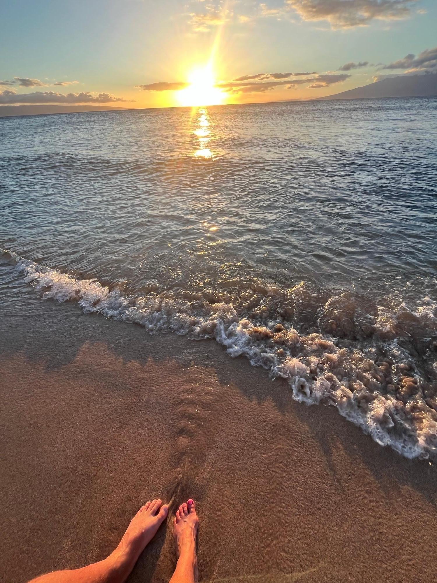 Feet in the sand at sunset