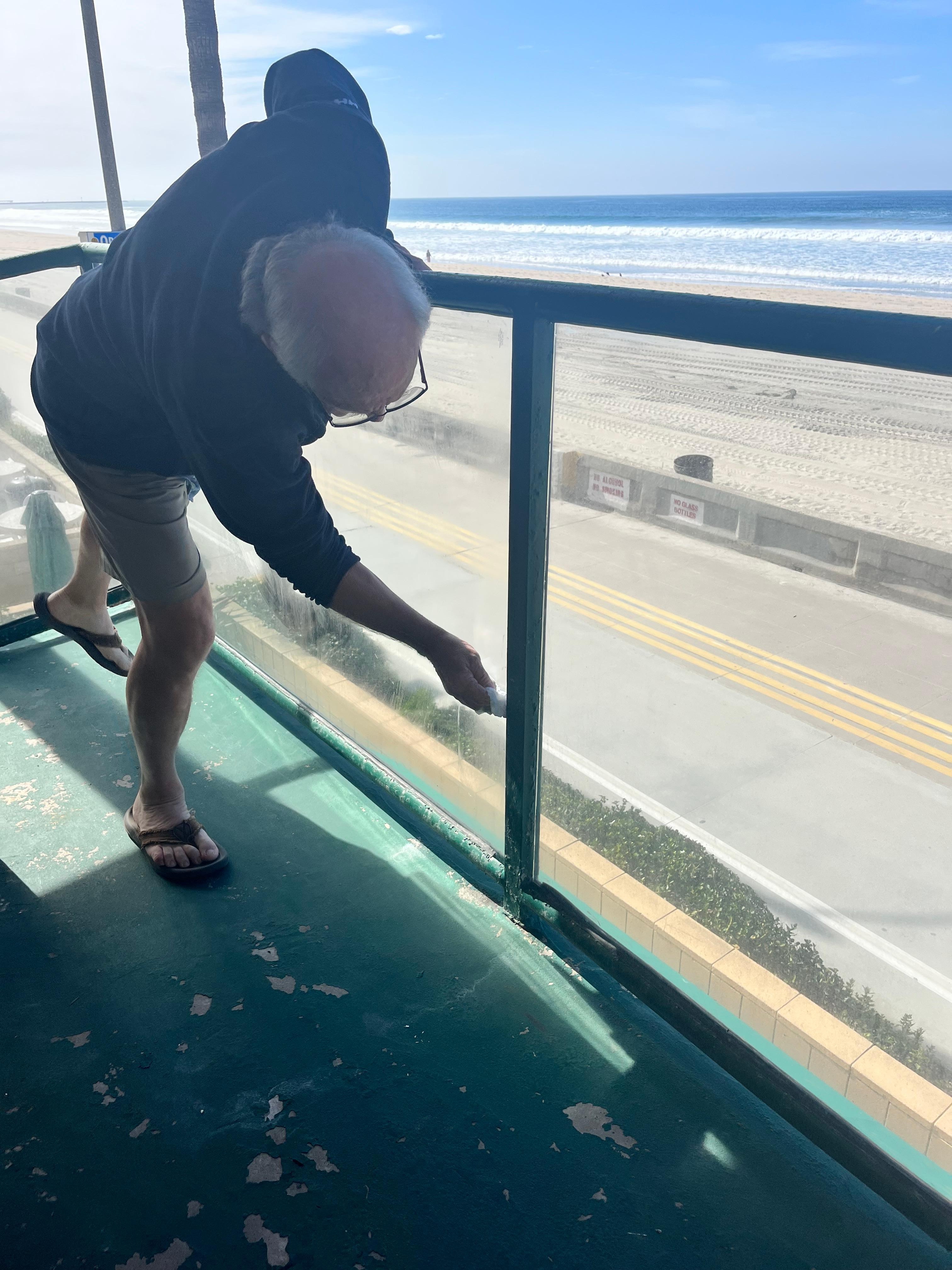 Husband cleaning deck window to see beach