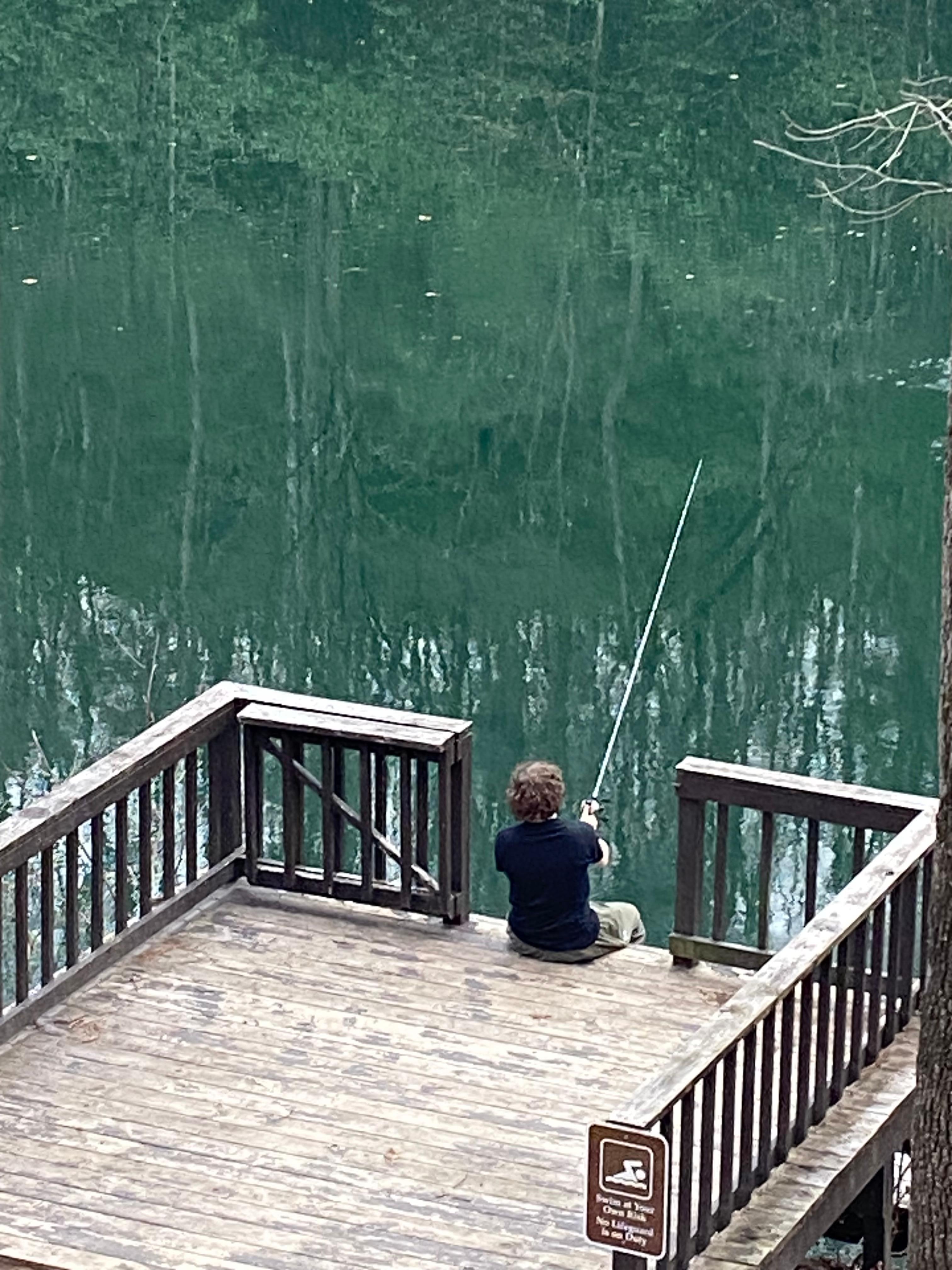 My son enjoying a peaceful afternoon fishing off the dock—one of those quiet moments that made the trip so special.