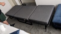 One of two twin, foldable cots next to one of two, teal twin slipper chairs.