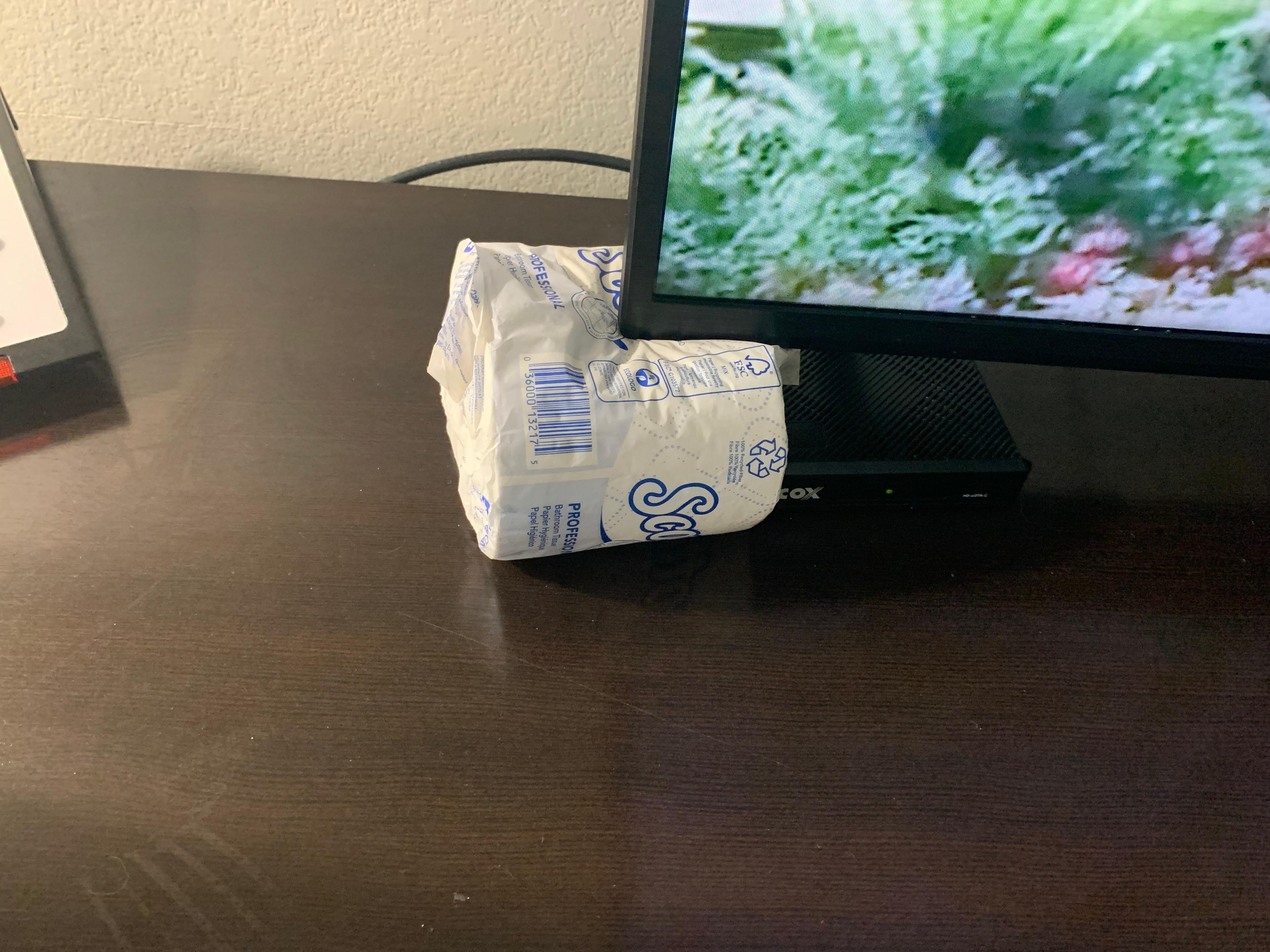 Broken TV stand supported by toilet paper. 