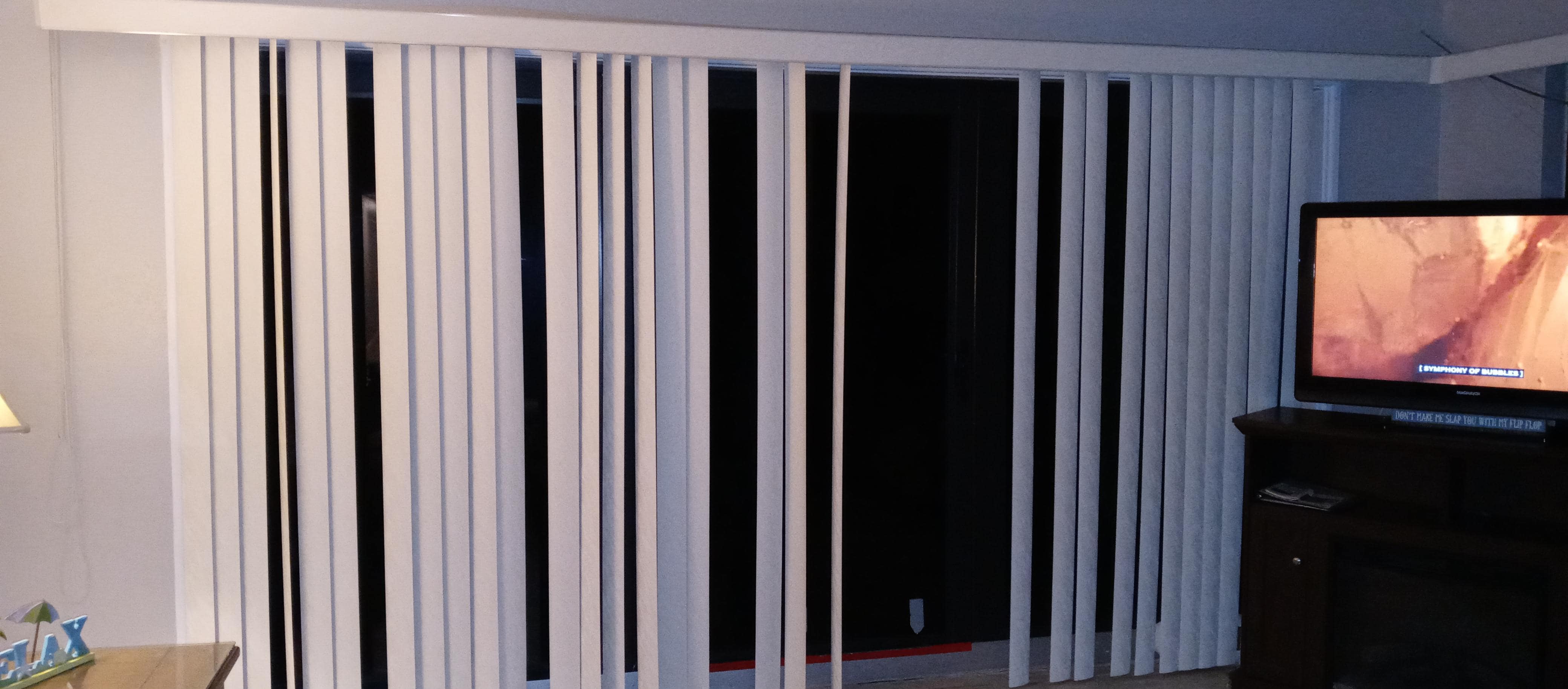 Patio blinds when closed. Missing several slats, which are located on floor behind couch.