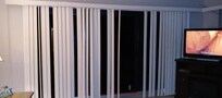 Patio blinds when closed. Missing several slats, which are located on floor behind couch.