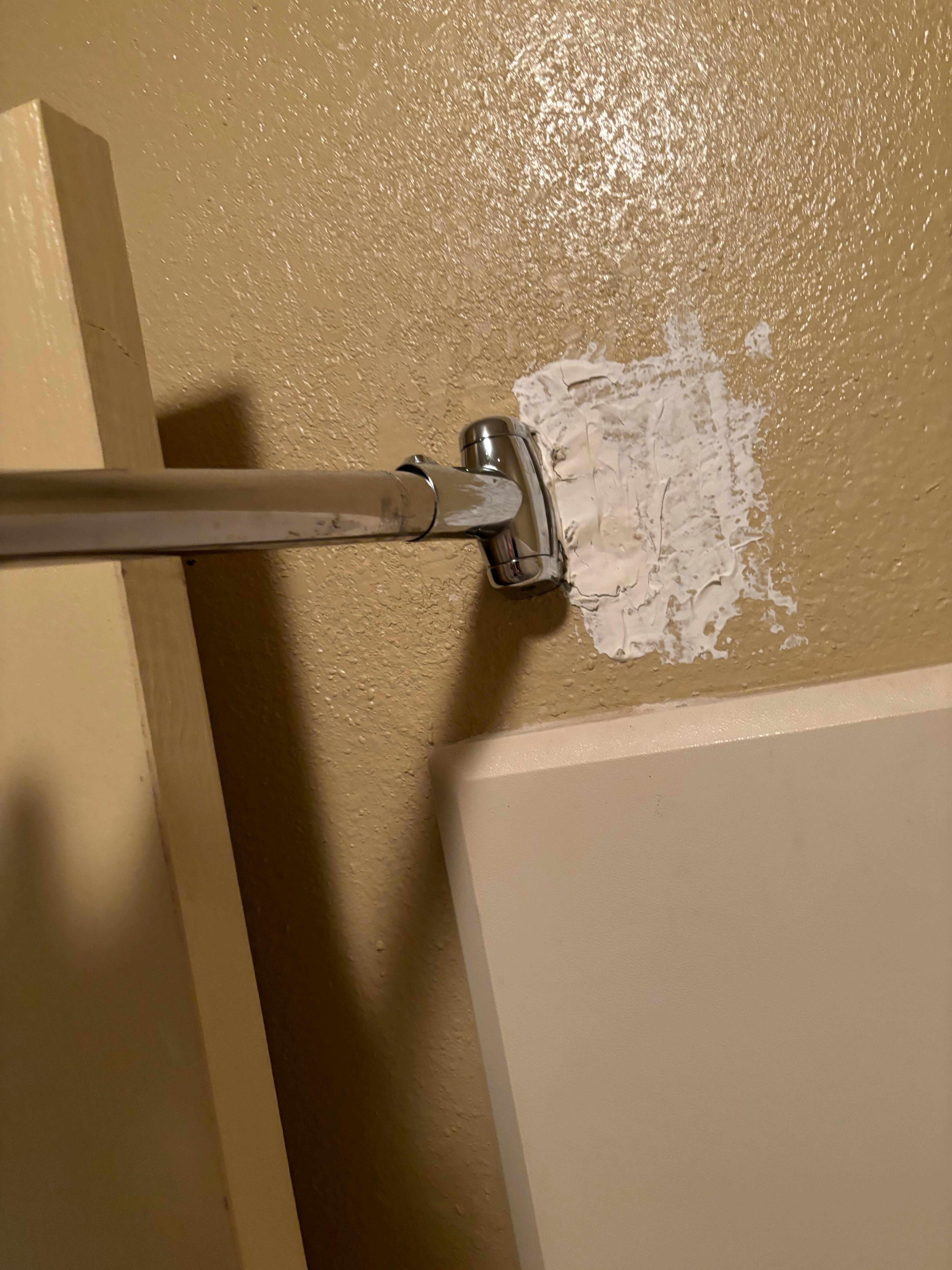 Shower curtain bar was reattached but poorly repaired. 