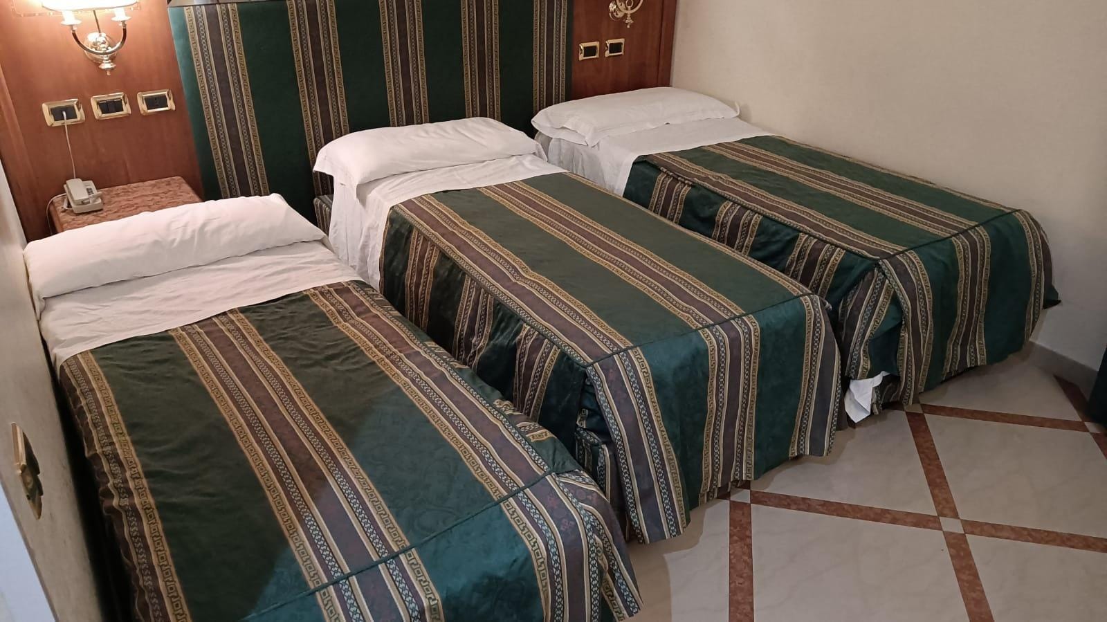 foto de la habitación que nos dieron, se puede ver el tamaño del colchón, espacio entre camas y una mesita detrás de una de las camas