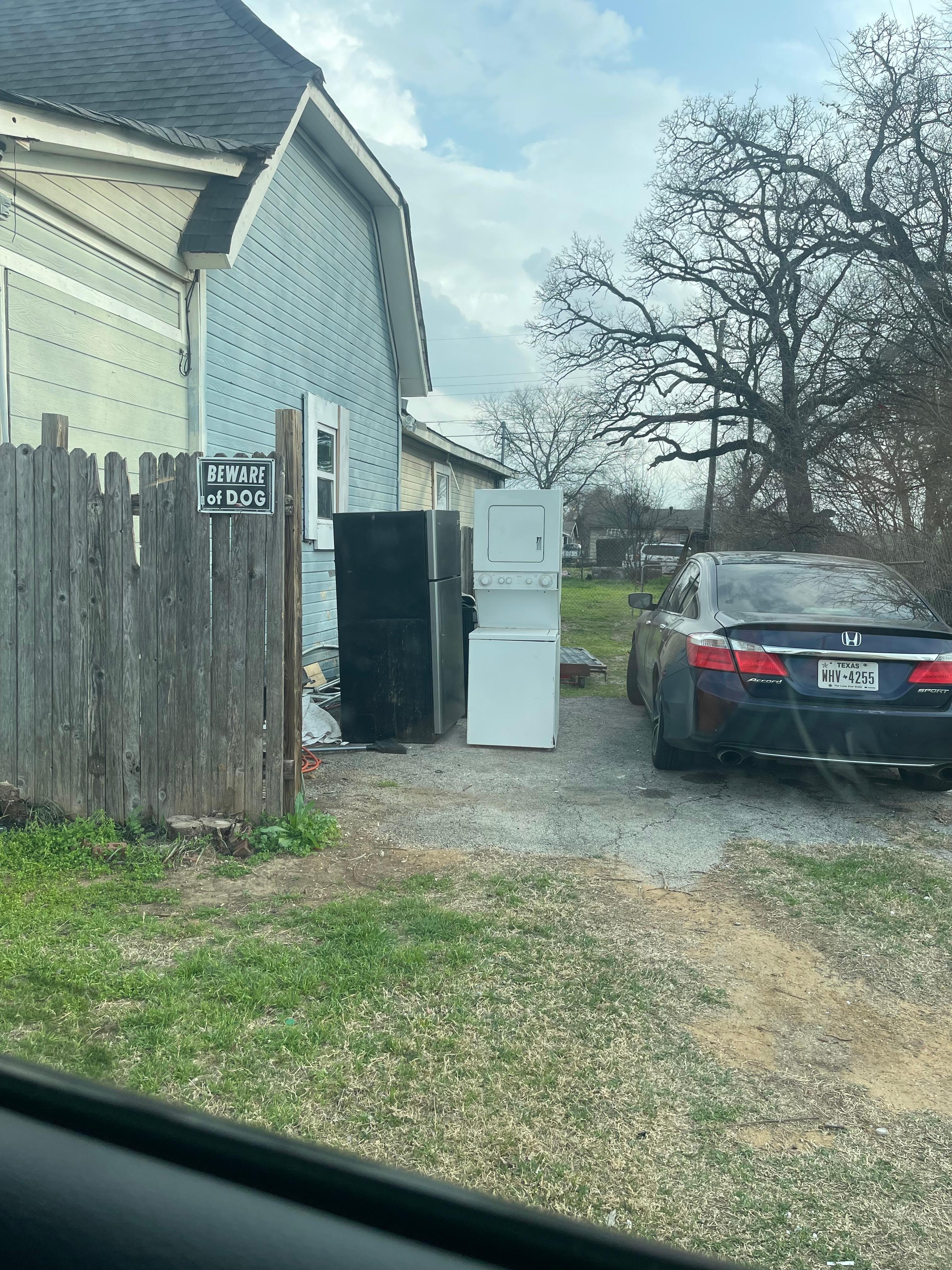 Broken appliances and car in driveway of house