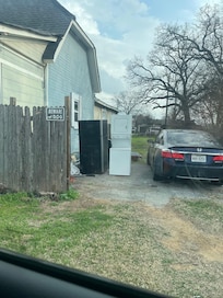Broken appliances and car in driveway of house