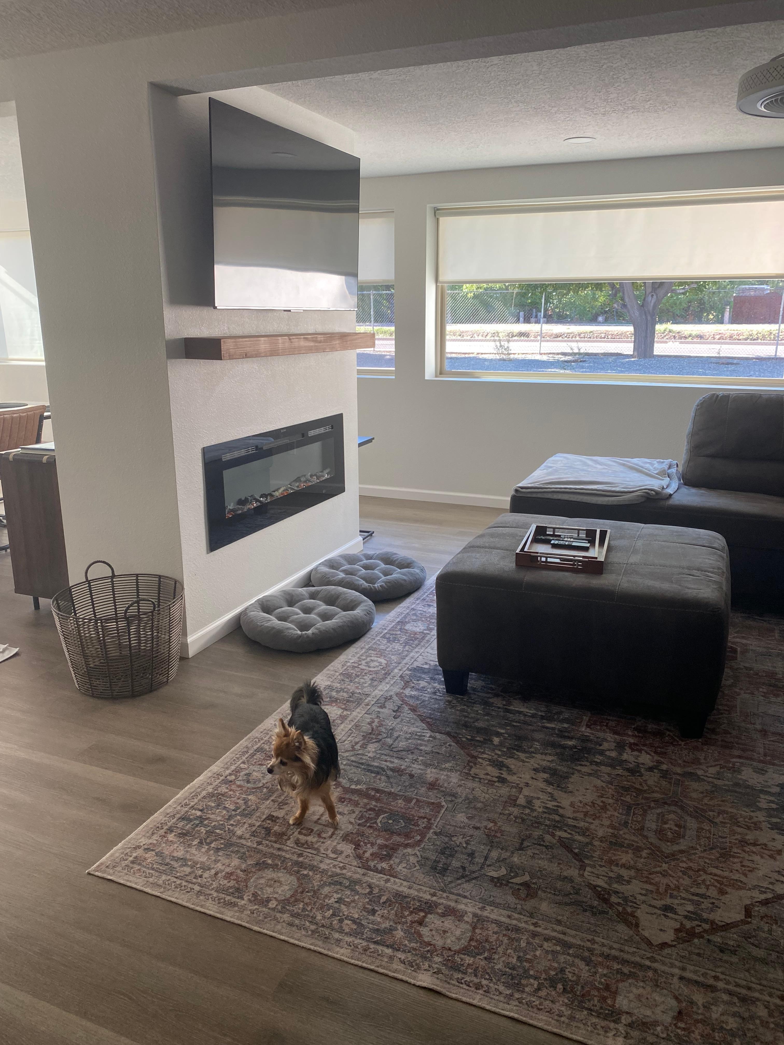 Living room area with large windows and views of the backyard. Beautiful fireplace and large television. 