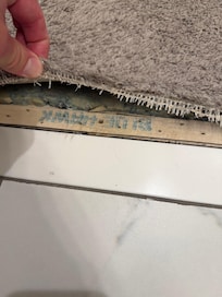 Carpet coming up, exposed carpet tacks by bathroom.