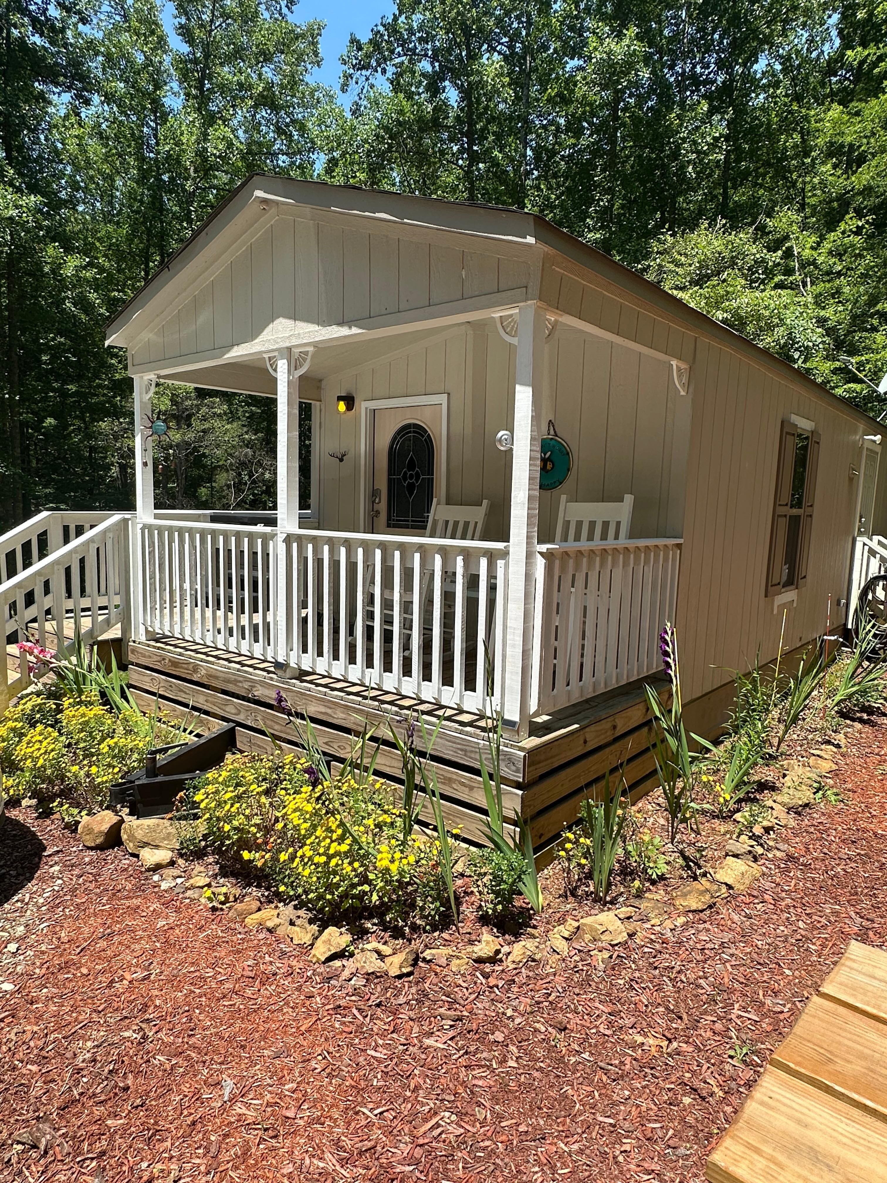 Outside of tiny home. Front porch with 2 rocking chairs and a table.