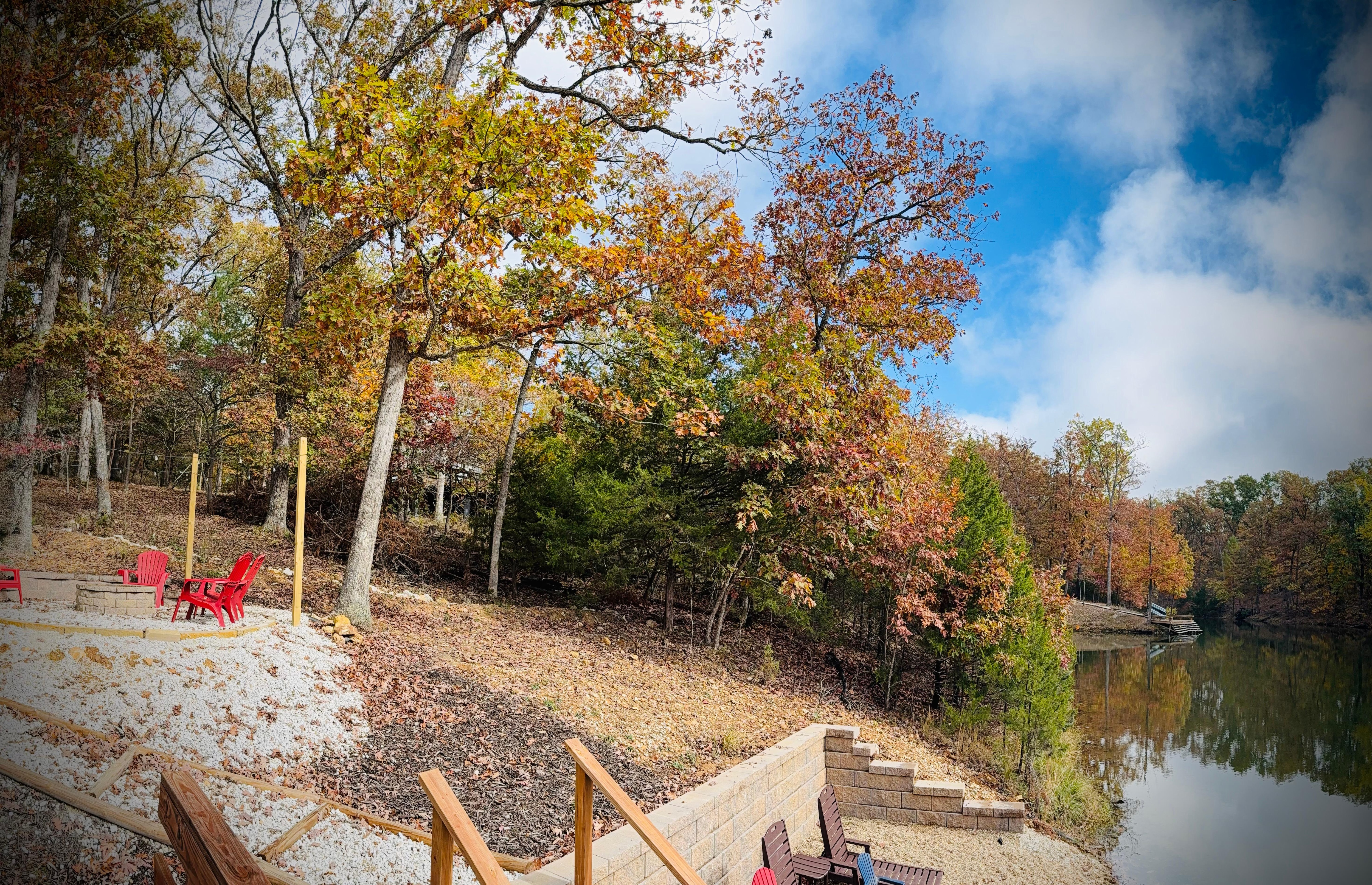 View from lakeside deck showing beach and fire pit with string lights. 