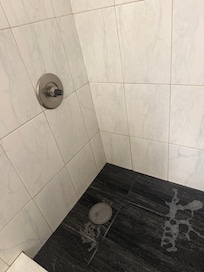 Shower with electrical tape for a handle and soapy standing water.