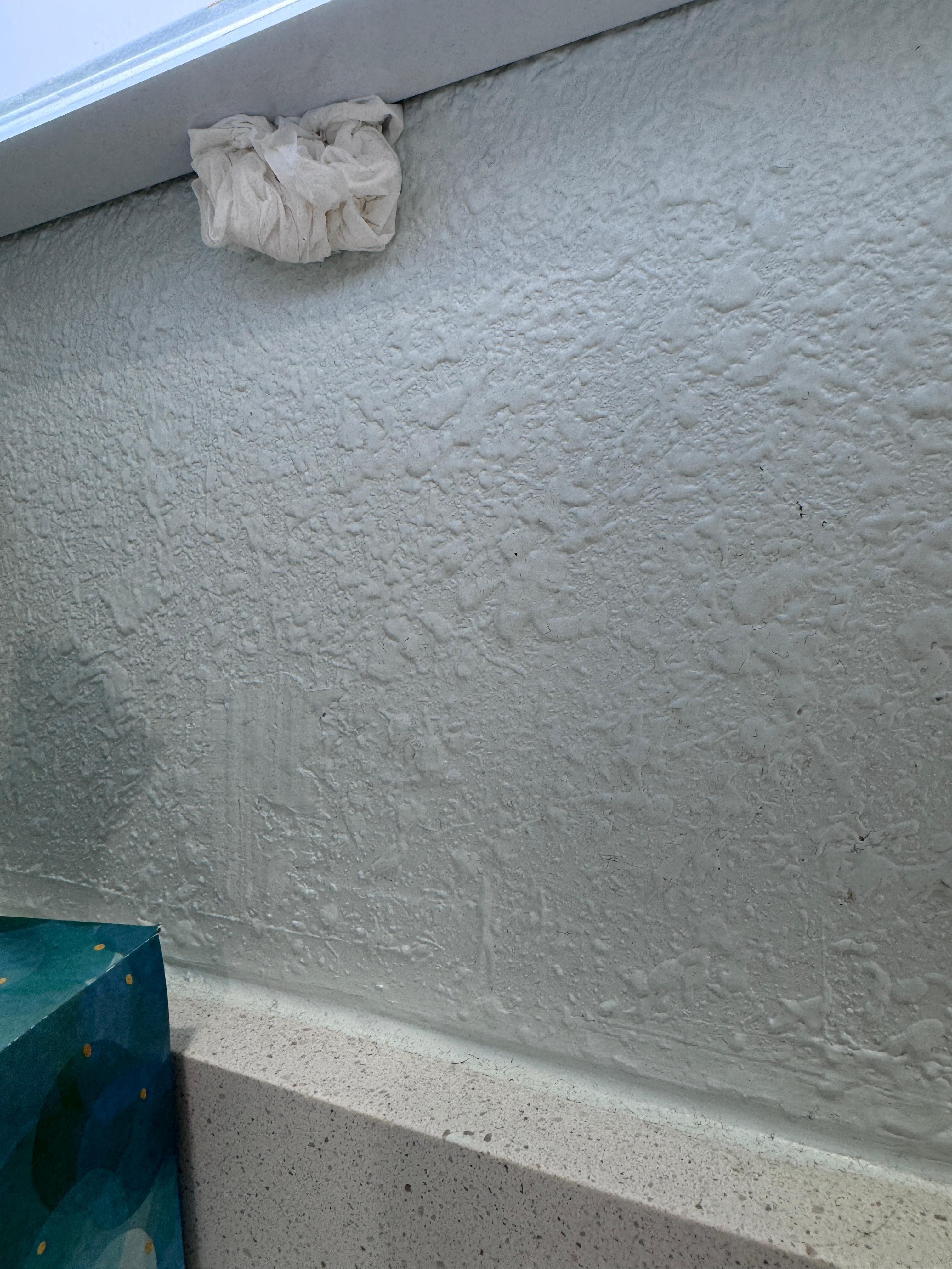 Wad of some sort stuck to the wall y see the mirror 