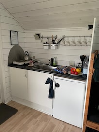 Tekøkken med køleskab og lille fryser og service til ca.4/6 Pers. Det eneste vi savnede var en si og en mellem skål. (Den viste kogeplade er blevet udskiftet under vores ophold) man kunne måske sætte hylder op - for ekstra plads.