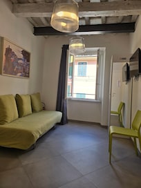 Romslig oppholdsrom med sofa, vakker himling, safe i skapet. Tørkesnor utenfor vinduet.