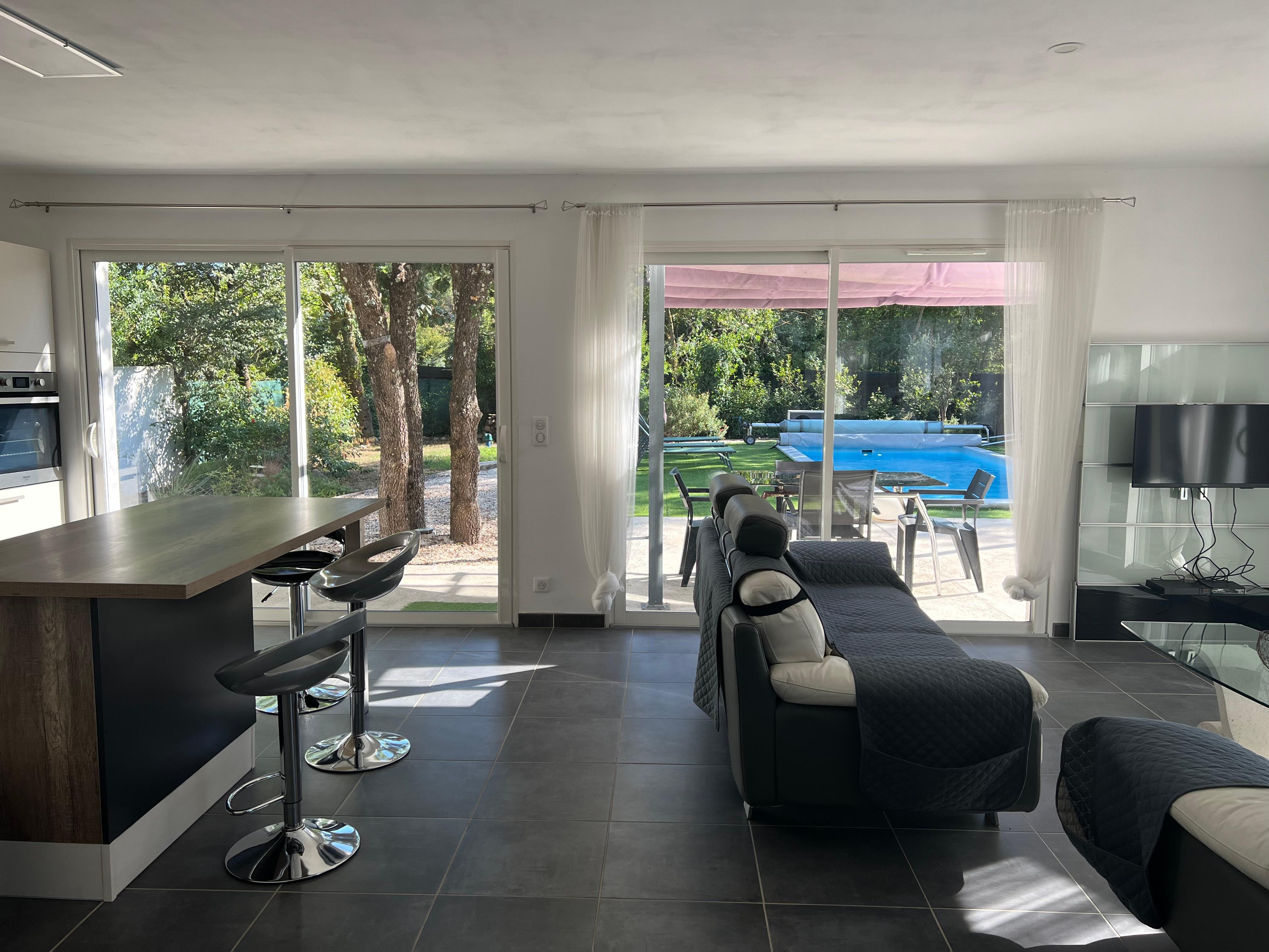 Séjour cuisine avec vue sur la terrasse et la piscine.