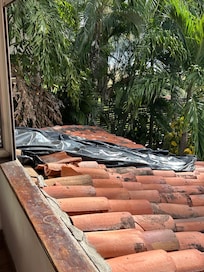 Broken roof tiles and tarpaulin above poolside bedroom