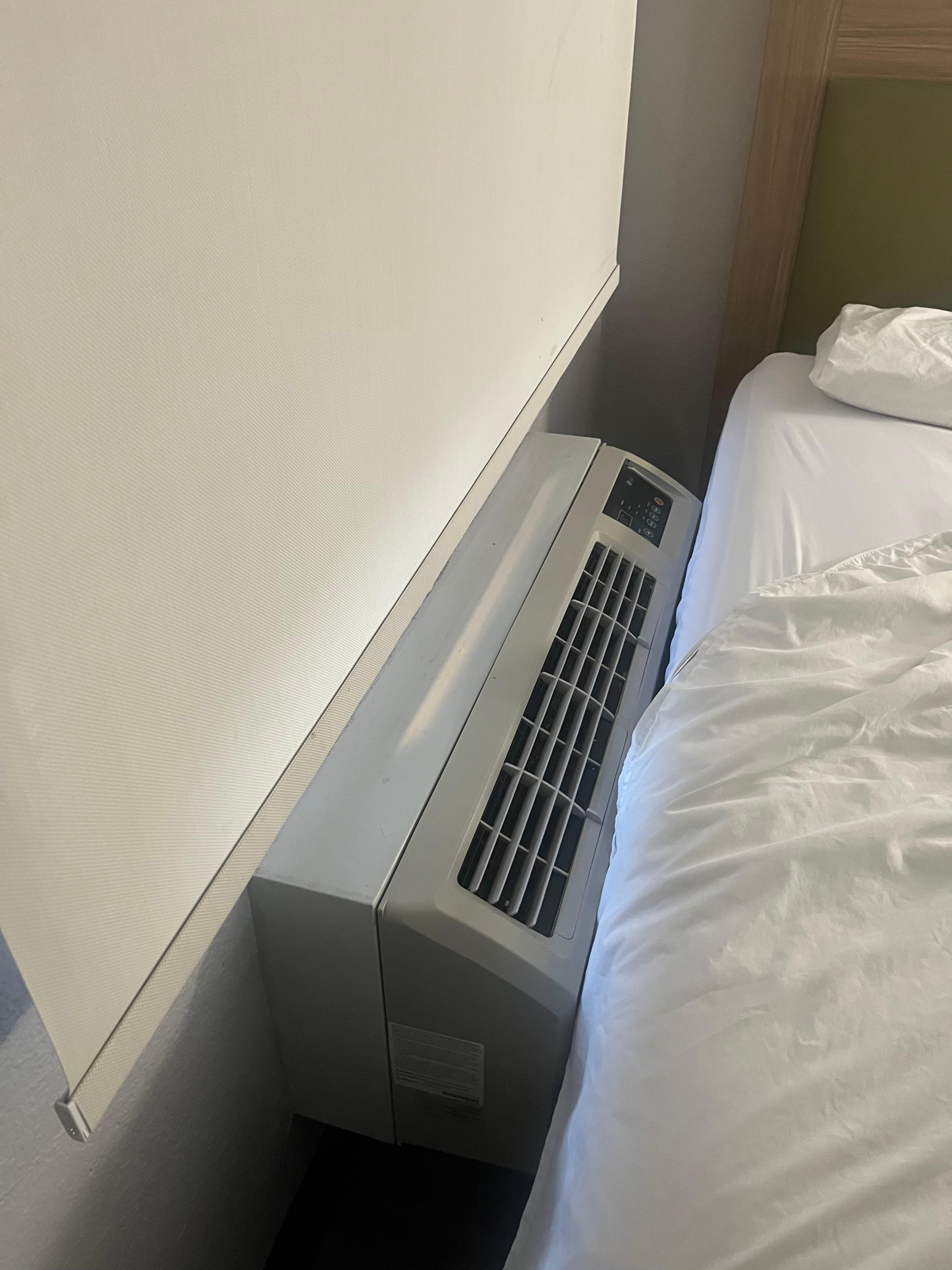 Beds against cooling unit making it necessary to climb on bed to open shade. Other bed against the wall. 