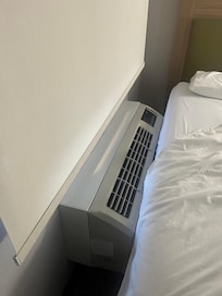 Beds against cooling unit making it necessary to climb on bed to open shade. Other bed against the wall.