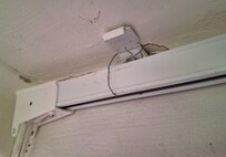 Curtain rod gerry-rigged with a thin piece of wire to hold the drape rod up.