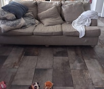 Couch in the living room with rip below the white blanket.