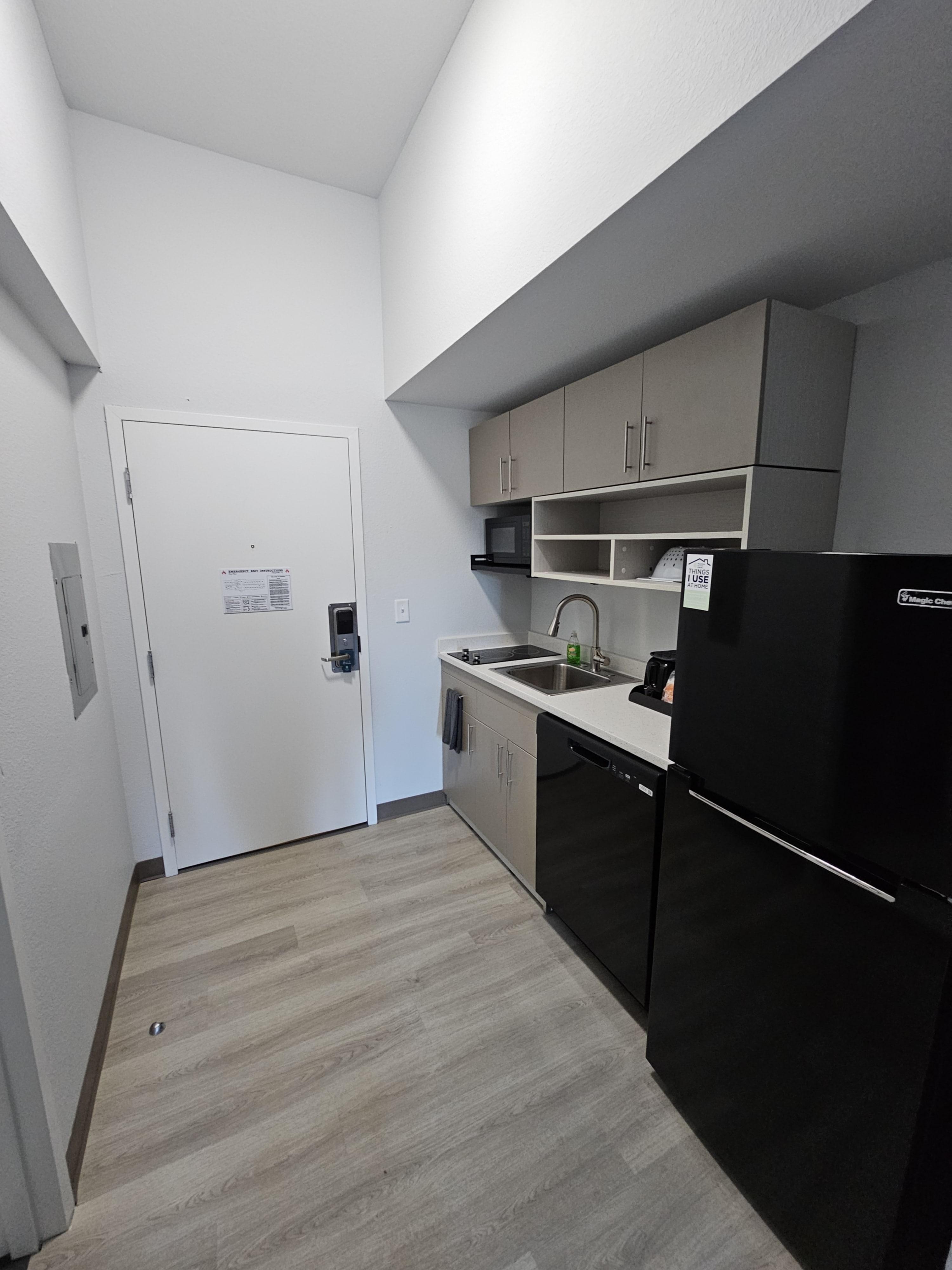 Kitchen area. There are glass plates, cups and kitchen utensils in the cabinets. Dishwasher soap is also there.