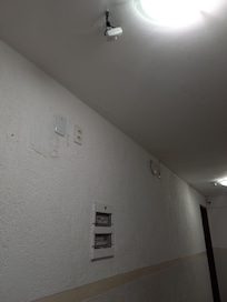 No corredor instalação elétrica solta, fios aparentes e quadro sem porta. Risco de curto circuito