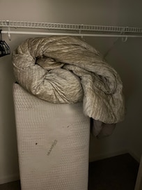 “extra bed” with dirty roll up mattress and dirty blankets on top