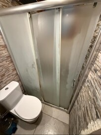 Bad mit schmutziger und defekter Duschtür