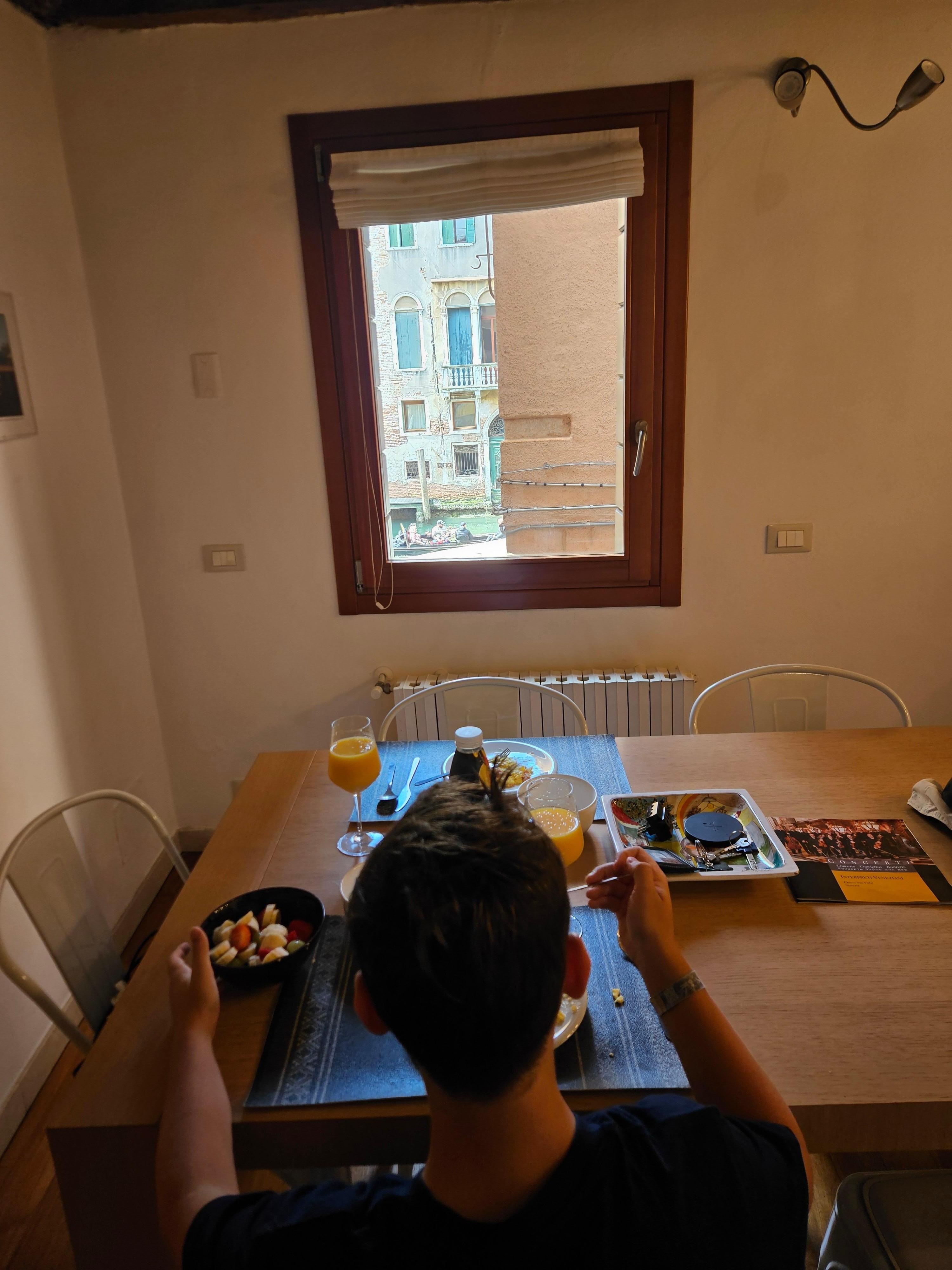 My 11-year old boy eating breakfast in the beautiful kitchen table watching out at the canal.